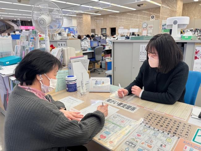 窓口での軟骨伝導イヤホンを使用している様子